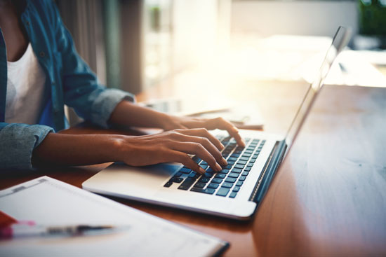 Femme tapant sur un clavier d'ordinateur portable