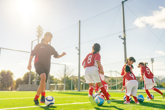 Equipe de football féminine jouant sur un terrain avec leur coach