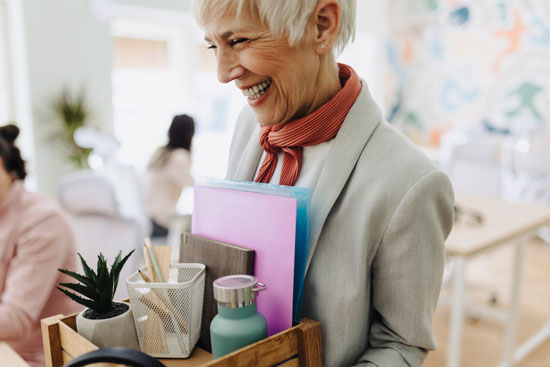 Femme souriante avec un carton, départ en retraite